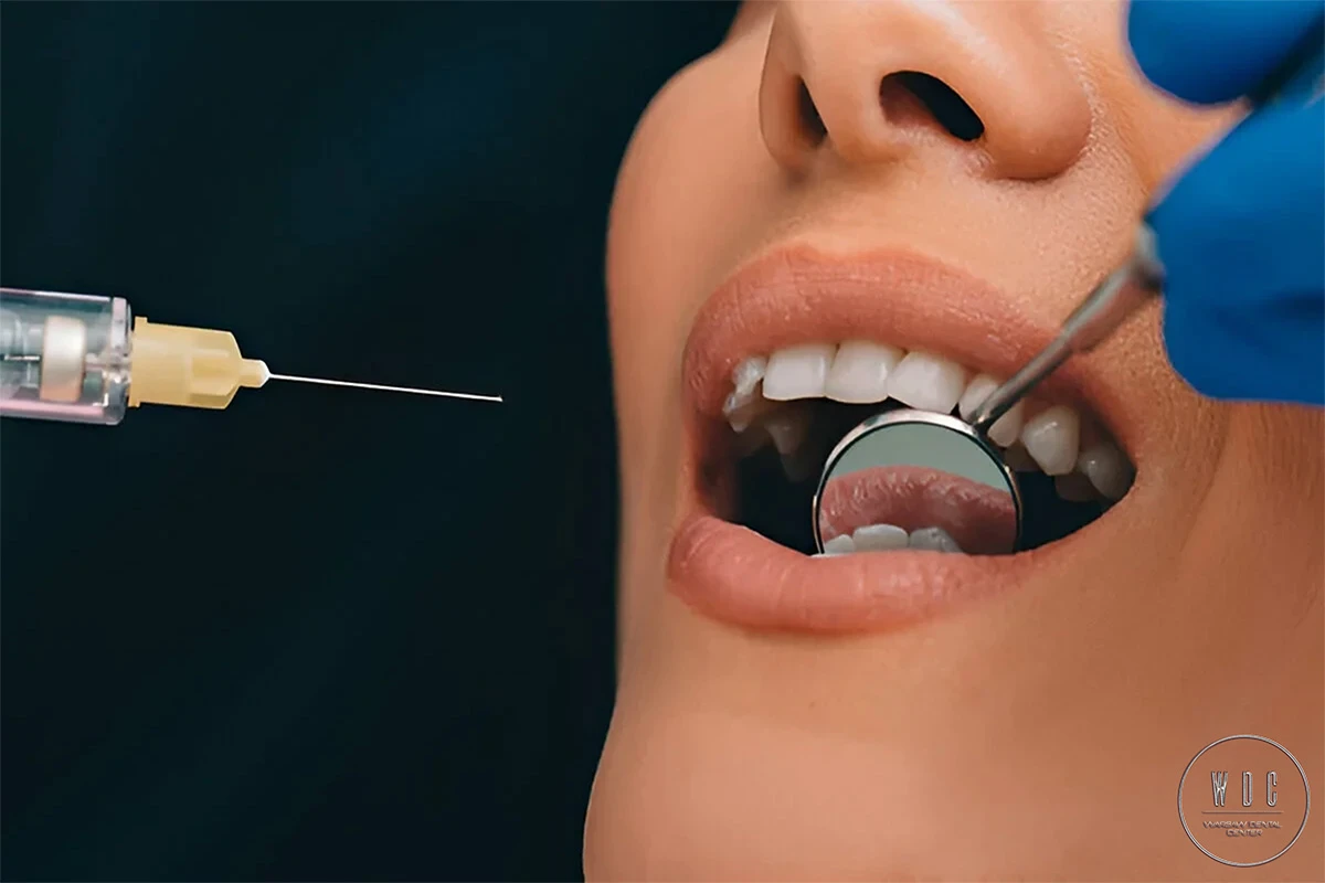 Anesthesia injected near the open woman's mouth before dental treatment.