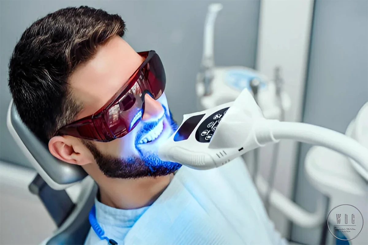Mężczyzna poddający się zabiegowi wybielania zębów w fotelu dentystycznym.