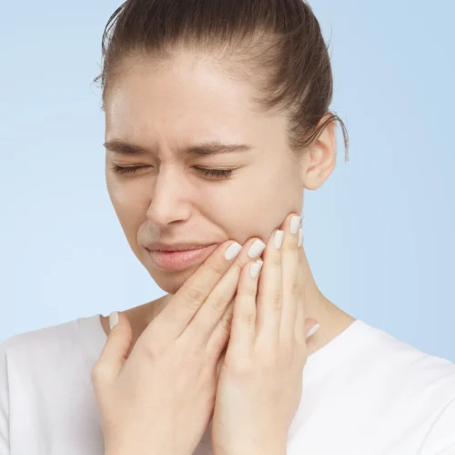Closeup of beautiful young woman isolated on blue background touching her face and closing eyes with expression of horrible suffer from health problem and aching tooth, showing dissatisfaction